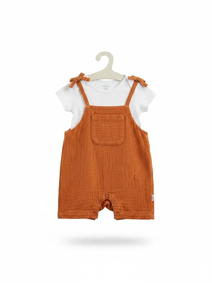 Elise Fay infant two-piece set with a white short-sleeve bodysuit and rust-colored muslin shortall with tie straps.